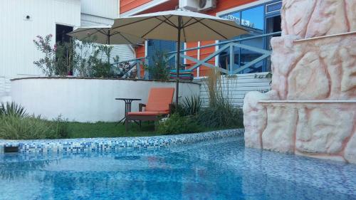 奇姆肯特Sapar Budget Hotel的一个带遮阳伞、椅子和桌子的游泳池