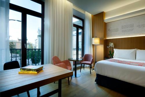 格拉纳达Áurea Catedral by Eurostars Hotel Company的酒店客房带一张床、一张桌子、一张床和窗户。