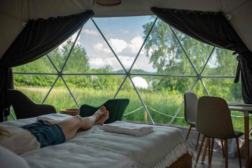 ManiowyBiała Czapla Glamping z balią nad jeziorem czorsztyńskim的躺在帐篷里的床上的人