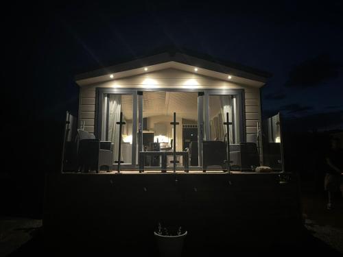 PlumblandLake District Luxury Lodge的夜晚门廊上放有屏风的房子