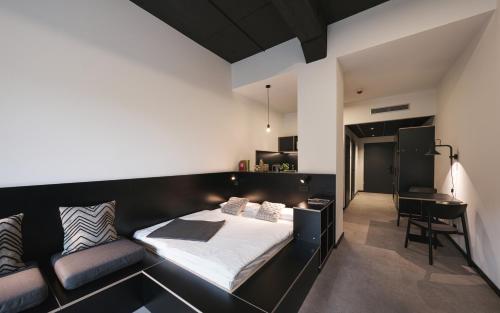 诺伊斯MoLiving - Design Hotel & Apartments Düsseldorf-Neuss的一间卧室配有一张黑色的床和一张书桌