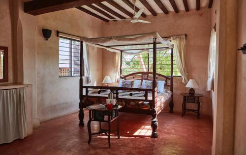 拉穆香蕉旅馆及健康中心的一间卧室设有天蓬床和窗户。