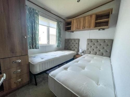 萨克斯曼德姆Beautiful Caravan With Decking At Carlton Meres Holiday Park, Suffolk Ref 60022m的一间小卧室,配有两张床和窗户