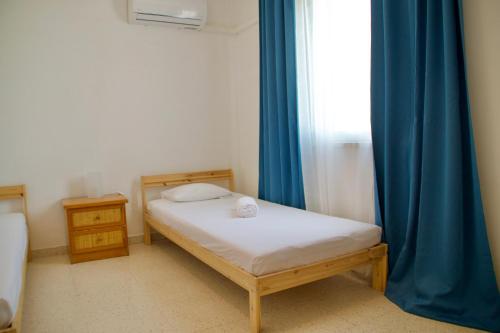 梅内乌Yiallos Village Apt. A101的一间小卧室,配有床和蓝色窗帘