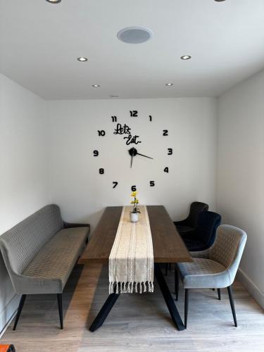 埃尔沃斯Luxury West London 3BR House, Cul De Sac的餐桌、椅子和墙上的时钟