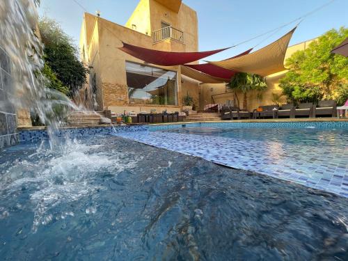 索瓦马Orient Villa-Dead Sea的一座大楼前的游泳池,带喷泉
