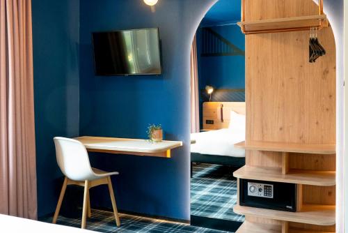 科尔马Ibis Styles Colmar Centre的一间拥有蓝色墙壁、一张桌子和一张床的房间