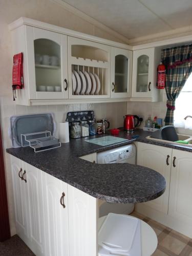 英戈尔德梅尔斯Cosy comfort的厨房配有白色橱柜和花岗岩台面
