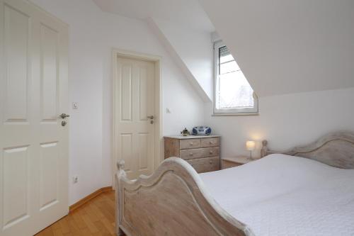 博尔滕哈根Sanddornweg Wohnung 13 a的白色的卧室设有床和窗户