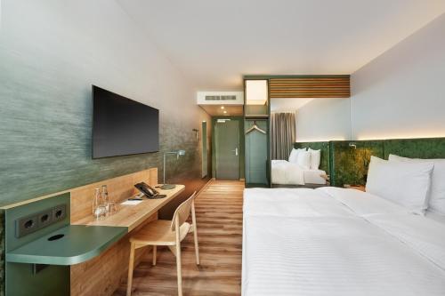 埃施伯恩H+ Hotel Frankfurt Eschborn的酒店客房设有一张大床和一张书桌。