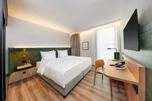 埃施伯恩H+ Hotel Frankfurt Eschborn的酒店客房配有一张床、一张书桌和一台电脑