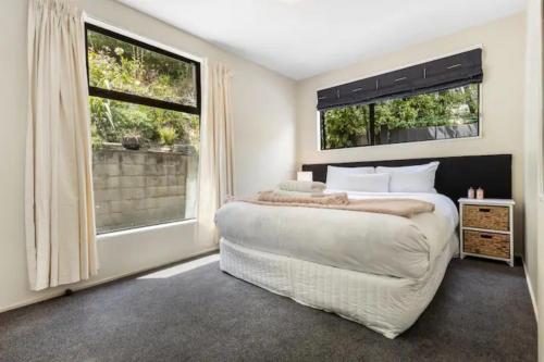 皇后镇The Alpine - Queenstown Holiday Home的一间卧室设有一张大床和两个窗户。