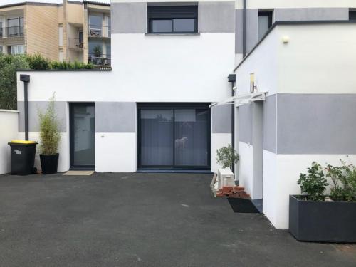 安格雷ANGLET petite Maison à 2 kms des plages et de Biarritz的白色的房子,前面有停车位