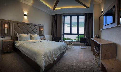 阿克恰阿巴德SIRT BUTİK HOTEL的酒店客房设有一张大床和一张书桌。