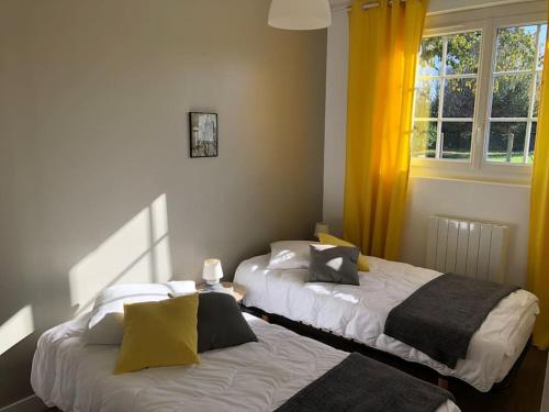 MenarsAU FIL DE L EAU的配有黄色窗帘的客房内的两张床