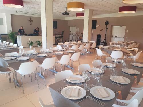 蒂勒尼亚Eliopoli Beach Hostel & Restaurant的一个带桌子和白色椅子的大型宴会厅