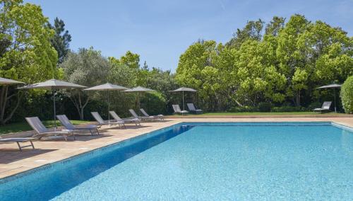 圣特罗佩Golf Resort & Country Club Saint-Tropez的一个带椅子和遮阳伞的游泳池