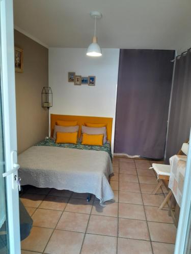 艾格-莫尔特AIGUES MORTES Studio de Vacances en Camargue的一间卧室配有带橙色枕头的床