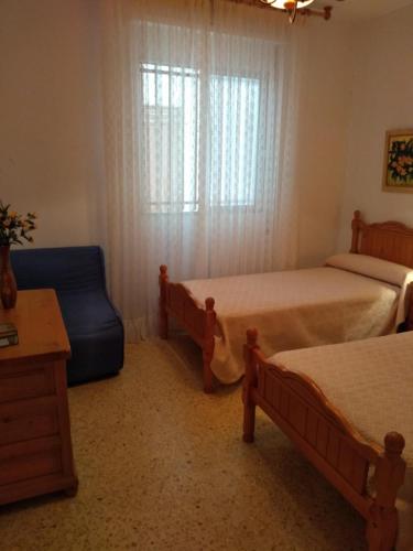 阿尔考斯布里Margaritas的一间卧室设有两张床、一把椅子和一个窗户。