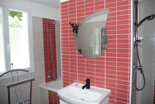 RouffignacLa Tour的红色瓷砖浴室设有水槽和镜子