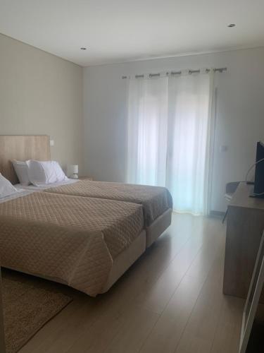 法蒂玛Apartamento Fátima Sanctuary的卧室配有一张带白色墙壁和木地板的大床