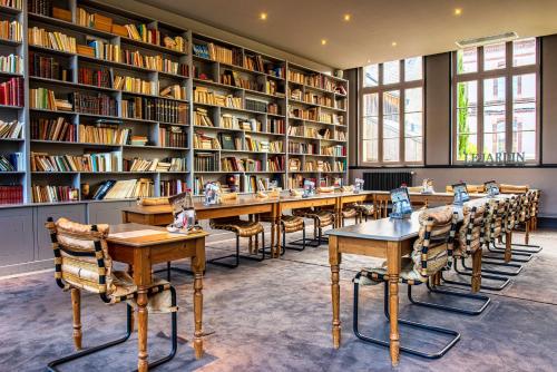 翁弗勒尔Les Maisons de Lea, a member of Radisson Individuals的图书馆配有桌椅和书架