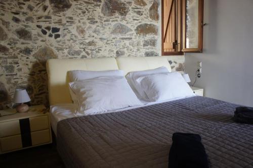 AmigdhalokeFálionAlegria stone house的一间卧室配有一张带白色枕头的床和石墙