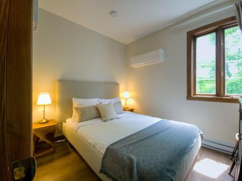 蒙特朗布朗Manoir 108-2/ Perfect getaway with POOL的一间卧室配有一张床、两盏灯和一个窗户。