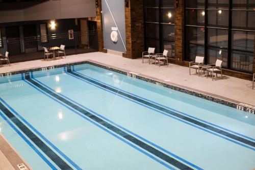圣克劳德Holiday Inn & Suites St. Cloud, an IHG Hotel的一个带桌椅的大型游泳池