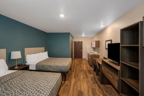 西棕榈滩WoodSpring Suites West Palm Beach的酒店客房设有两张床和一台平面电视。