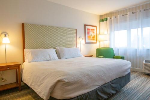 哥伦布Holiday Inn Express Columbus Airport Easton的一间卧室配有一张大床和一张绿色椅子