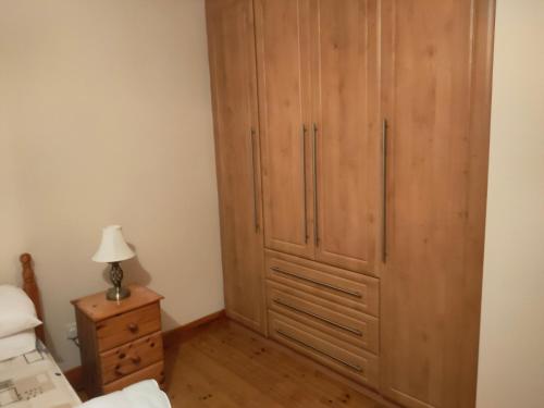 米尔敦马尔贝House的一间卧室配有一张位于床边的大型木制橱柜