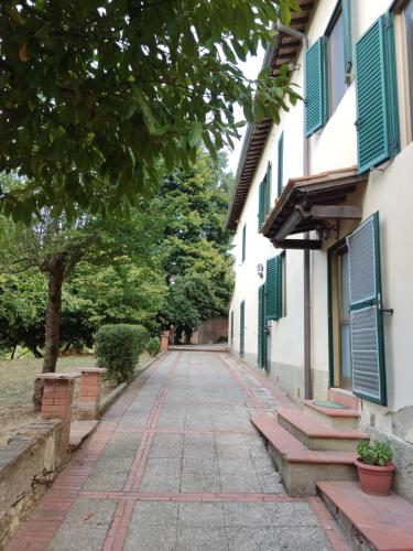 锡耶纳Agriturismo Le grondaie的两栋建筑之间一条鹅卵石街道,两栋建筑有绿色百叶窗