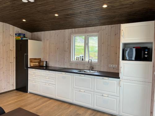 Birkimelur Strönd Guesthouse的厨房配有白色橱柜和黑色台面
