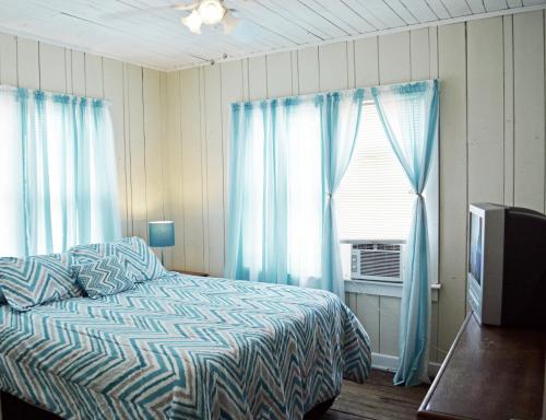 克利尔沃特Sunshine Cozy Cottage的一间卧室配有床和蓝色窗帘的窗户