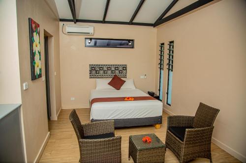 SigatokaSeatiki Resort Fiji On Coast的一间卧室配有一张床和两把椅子