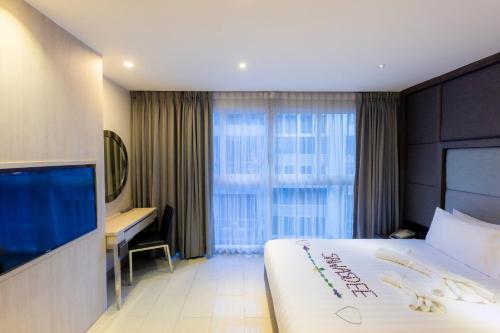 芭堤雅市中心Centara Life Avenue Hotel Pattaya的酒店客房设有一张大床和一台电视。
