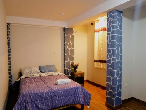 乌鲁班巴Cozy mountain house的一间卧室配有一张带紫色床罩的床