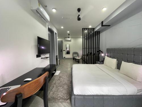 古尔冈BedChambers Luxurious Serviced Apartment in Gurgaon的一间卧室配有一张床、一张书桌和一台电视