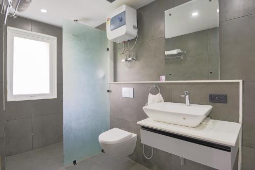 古尔冈BedChambers Luxurious Serviced Apartment in Gurgaon的一间带水槽和卫生间的浴室以及窗户。