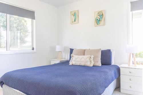 贝拉拉Nannys Beach House的白色卧室设有蓝色的床和2个窗户