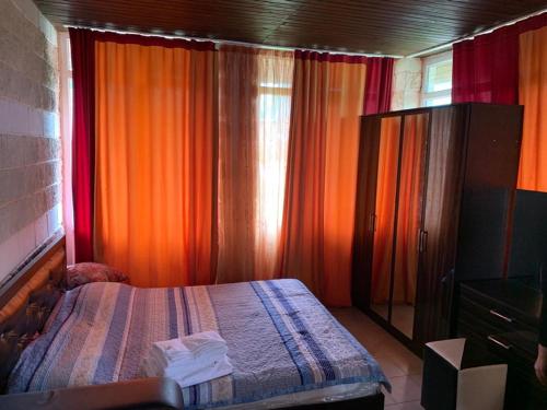 乔克-塔尔royal_beach_cottege的一间卧室配有橙色窗帘、一张床和一个梳妆台
