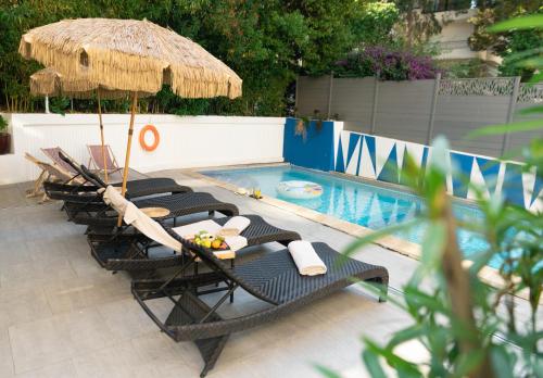 戛纳Juliana Hotel Cannes的一组椅子和一把遮阳伞,位于游泳池旁
