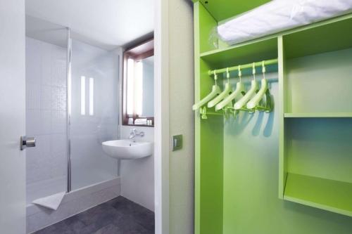 蓬图瓦兹钟楼塞吉庞托瓦斯酒店的浴室设有绿色的墙壁、水槽和淋浴。