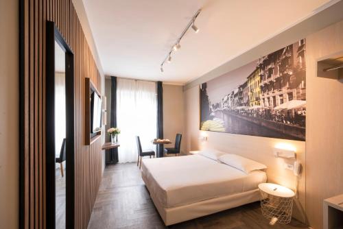 米兰Kleos Hotel Milano的酒店客房设有一张床,墙上挂有绘画作品