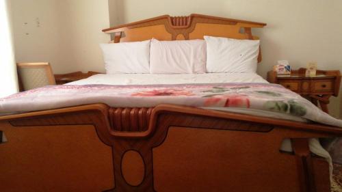 杜姆亚特阿尔加迪达赫1bd women的一间卧室配有一张木床和木制床头板