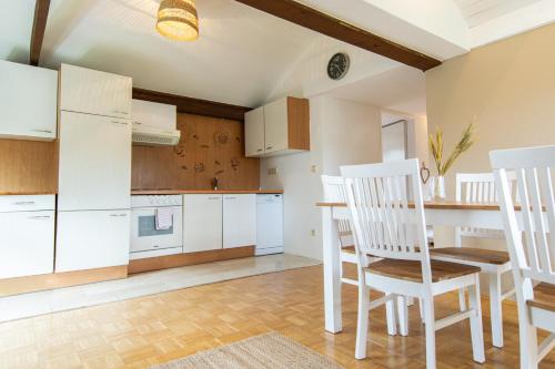 JormannsdorfLions Apartments - Erholung und Vergnügen in Bad Tatzmannsdorf的厨房配有白色橱柜和桌椅