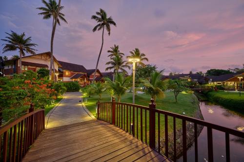 库玛拉孔Gokulam Grand Resort & Spa, Kumarakom的通往棕榈树房屋的木制走道