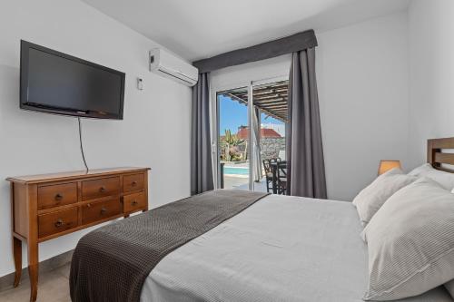 普拉亚布兰卡Villa Patos的一间卧室配有一张床、一台电视和一个阳台
