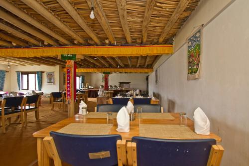 斯潘格米克Pangong Retreat Camp的用餐室配有木桌和蓝色椅子